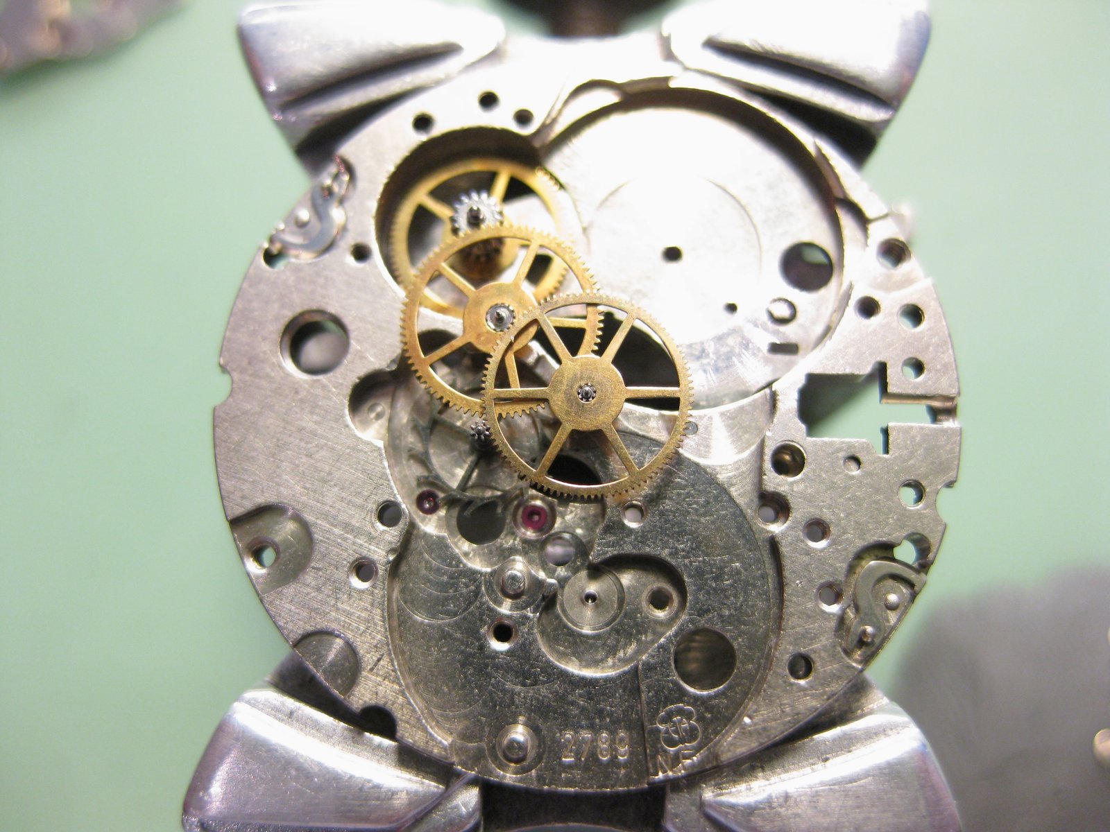 Detalle del interior de un movimiento de reloj mecánico calibre 2789 , mostrando engranajes dorados, rueda de escape con rubí, tornillo de regulación y placa principal con perforaciones y joyas visibles.