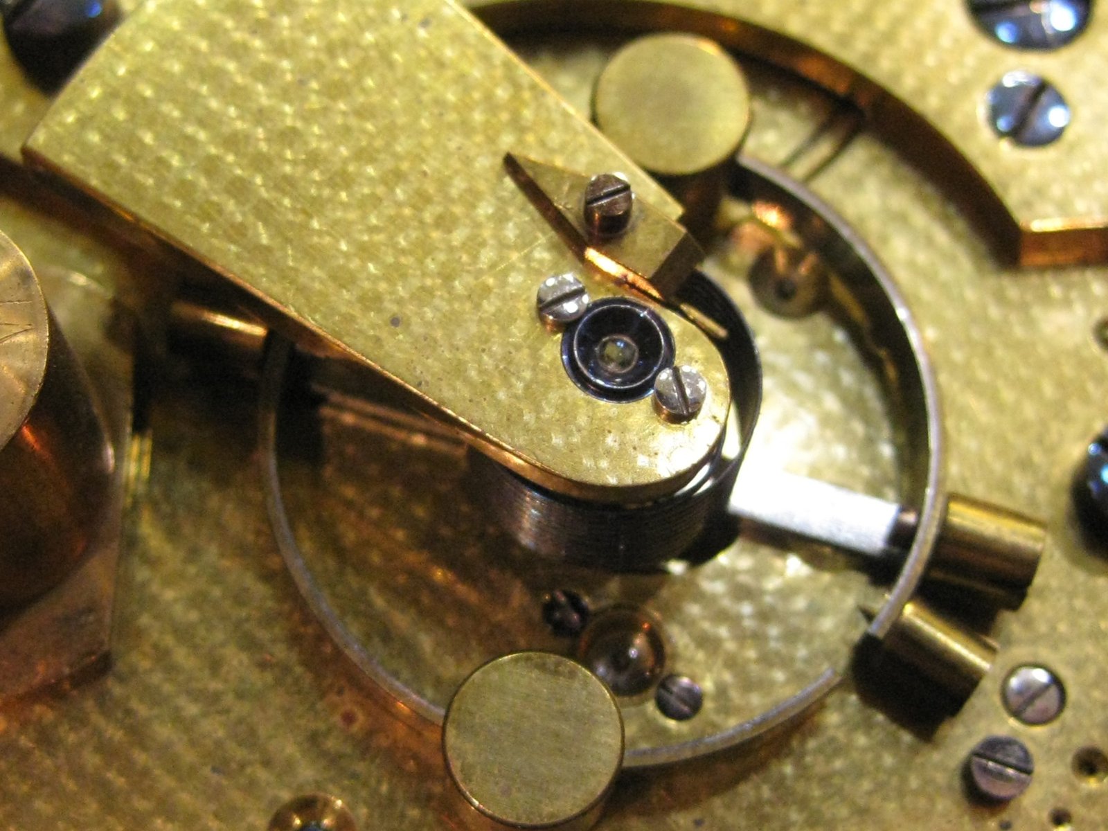Vista superior del regulador y componentes de ajuste en el interior de un reloj antiguo