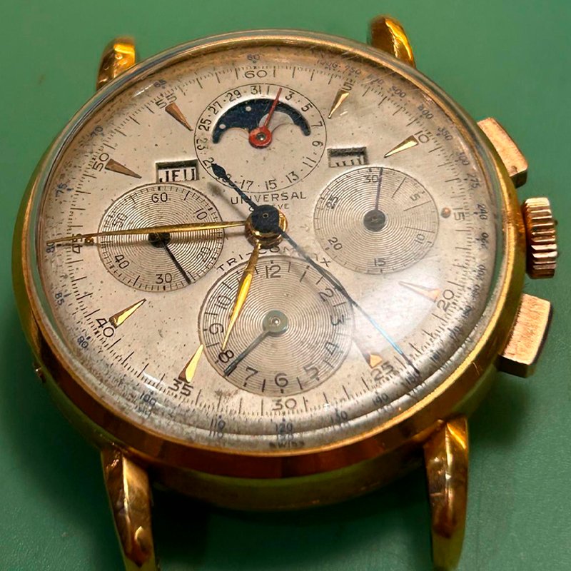 Reloj Universal Genève Tri-Compax con esfera clásica sobre mesa de trabajo